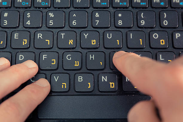 istock Man typing on keyboard with letters in Hebrew and English 505402094
