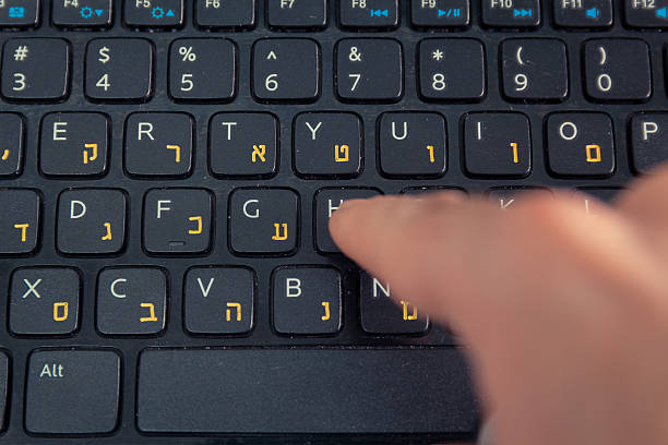 istock Man typing on keyboard with letters in Hebrew and English 505402200