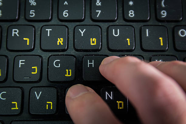istock Man typing on keyboard with letters in Hebrew and English 505402748
