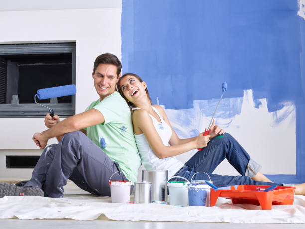 istock Couple sitting back to back with roller brushes in hand 505408832