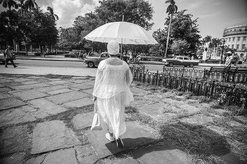 Havana, Cuba - November 6, 2015: Large plaza at the center of old Havana, near Capitolio. Woman in white, with white umbrella walking on the plaza. One of the 