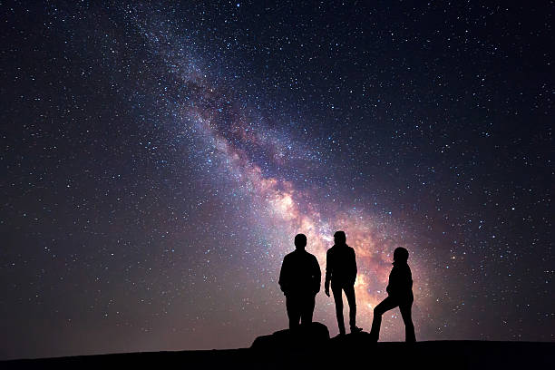 Milky Way. Night sky and silhouette of a family Milky Way. Night sky with stars and silhouette of a happy family with raised-up arms milky way photos stock pictures, royalty-free photos & images