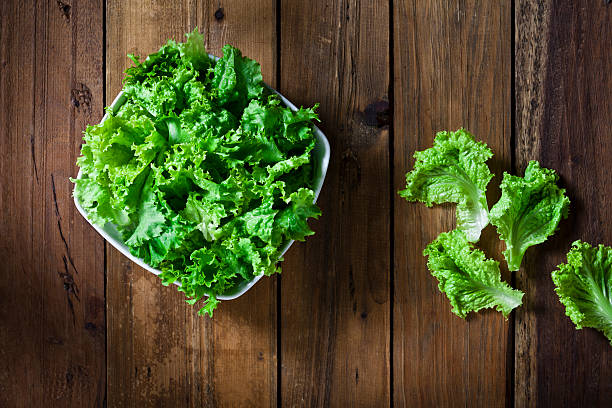 Organic lettuce bowl shot from above on rustic wood table.  DSRL studio photo taken with Canon EOS 5D Mk II and Canon EF 70-200mm f/2.8L IS II USM Telephoto Zoom Lens