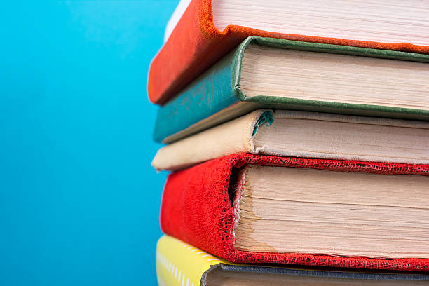 istock Stack of colorful hardback books, open book on blue background 505410900