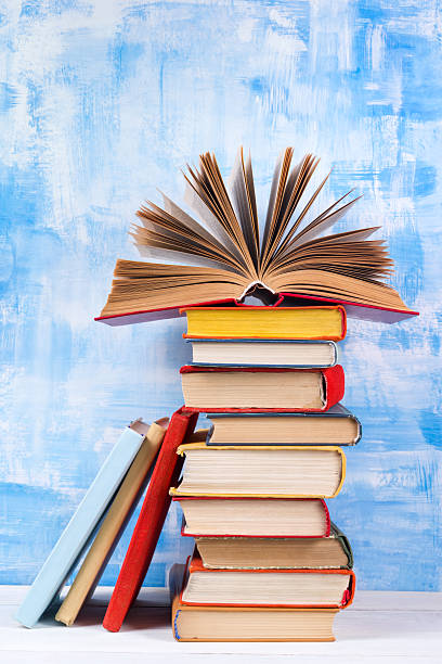 istock Stack of colorful hardback books, open book on blue background 505411996