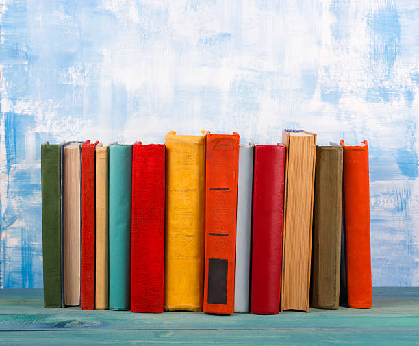 istock Stack of colorful hardback books, open book on blue background 505412088
