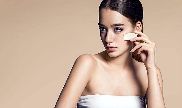 Young woman applying cosmetic on face with sponge