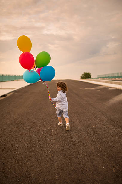 niedliche kinder laufen mit bunten ballons auf einer brücke. - child balloon happiness cheerful stock-fotos und bilder
