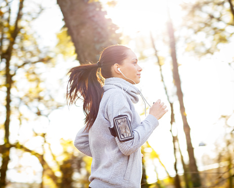 Sporty young woman running in the park and listening to music. Sport lifestyle. Motion blur.