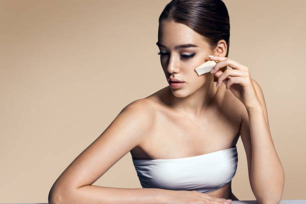 istock Beautiful woman applying foundation on face with sponge 505415282