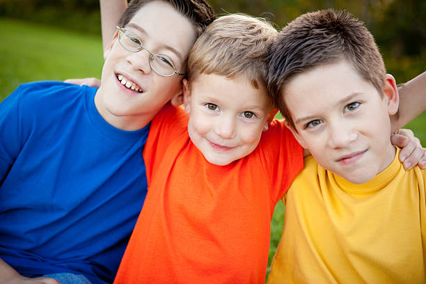 istock Three Happy Boys Sitting Together Outside 505415482