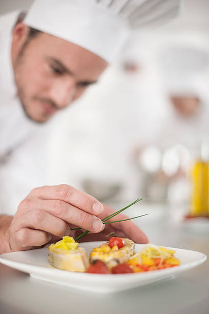 istock closeup on chef's hands garnishing a plate 505438239