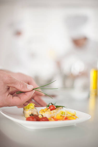 istock closeup on chef's hands garnishing a plate 505438247