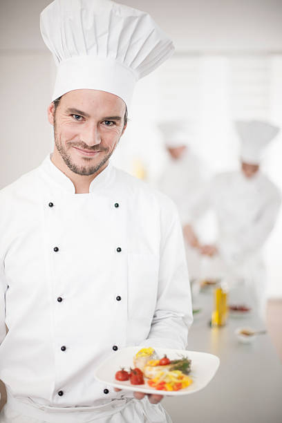 istock chef presenting a dish with his team in background 505439115