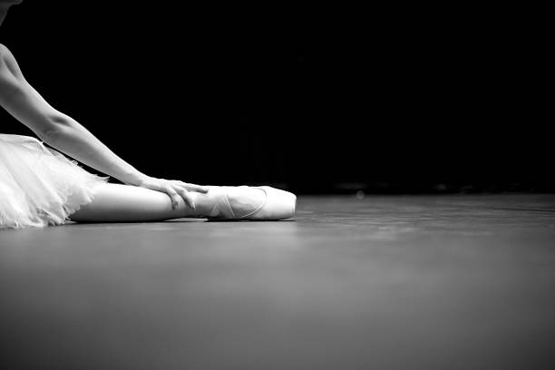 Hand and leg of ballerina sitting in split, monochrome