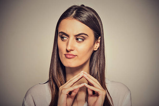 sneaky, sly, scheming woman plotting something Closeup portrait of sneaky, sly, scheming young woman plotting something isolated on gray background. Negative human emotions, facial expressions, feelings, attitude slander stock pictures, royalty-free photos & images