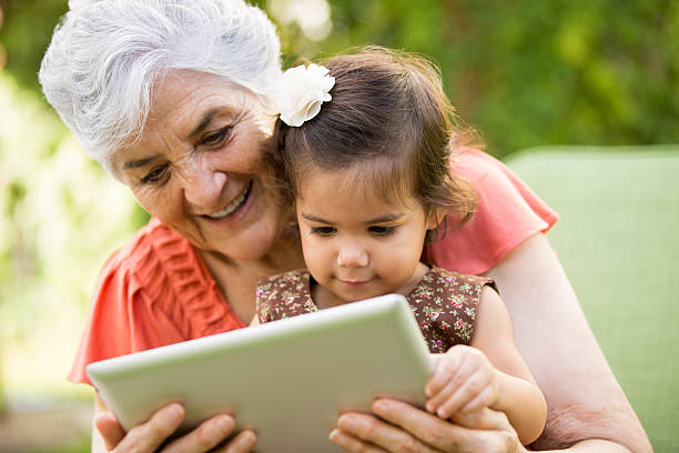 Grandmother showing tablet to grandchild A grandmother showing tablet to her grandchild. hispanic grandmother stock pictures, royalty-free photos & images
