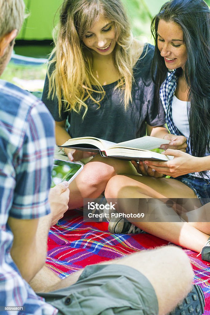 Group of friends relaxing at camping Group of friends relaxing at camping reading a book and using digital tablet 20-24 Years Stock Photo