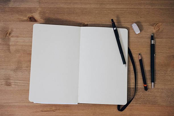 Blank sketchbook on wooden table with crayons