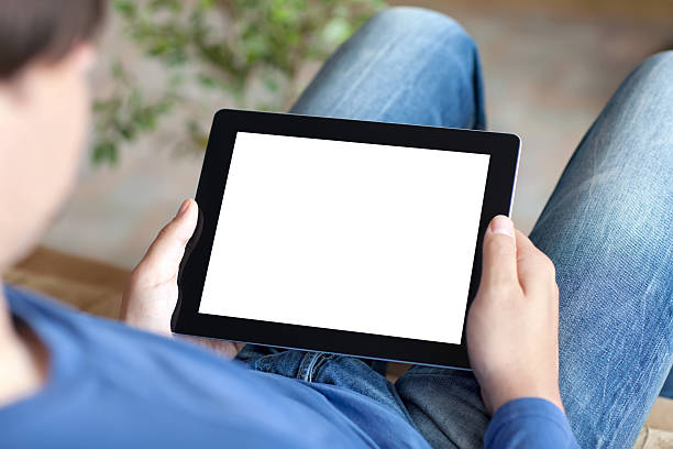 istock man sitting on sofa and holding tablet with isolated screen 505469199