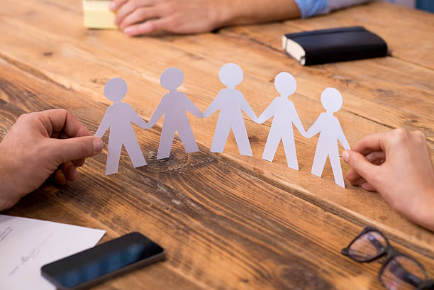 Business unity concept Close up of hands of man and woman holding paper people chain. Two businesspeople holding paper man chain depicting solidarity and friendship. Closeup of symbol of unity and strength and togetherness. people in a row photos stock pictures, royalty-free photos & images