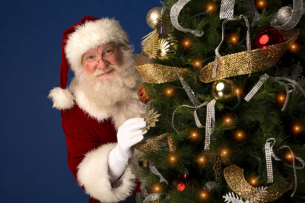 istock Santa Claus looking from behind a Christmas Tree 505471671