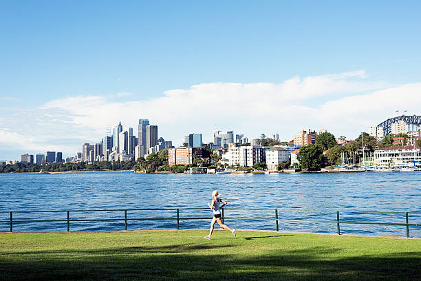 Fit young woman enjoying an early morning run outdoors alongside the waters edge in the park.