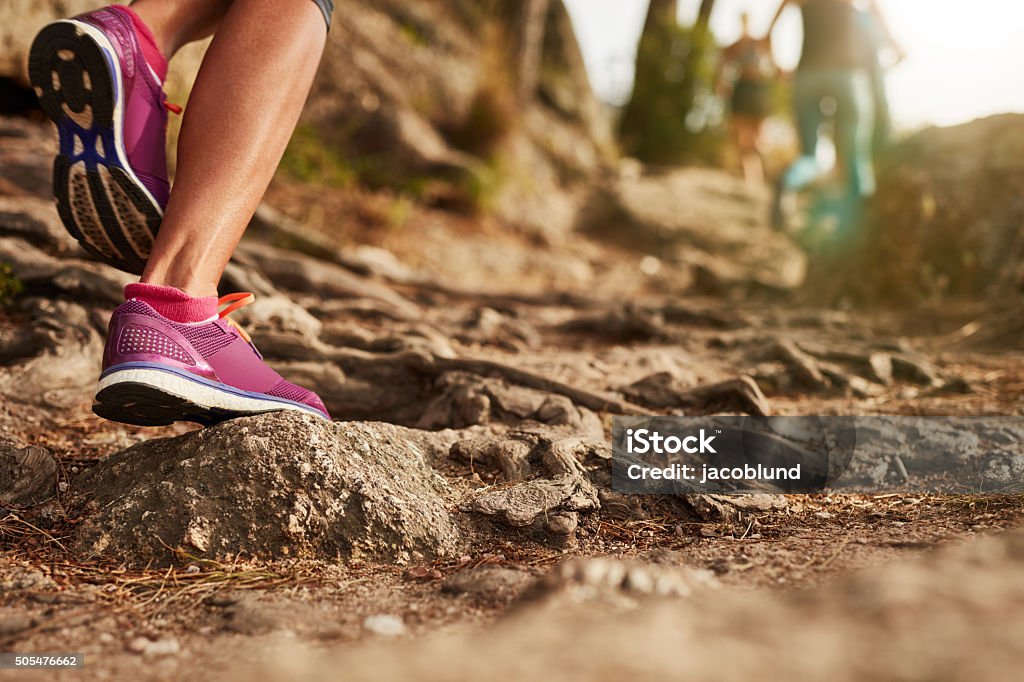 Athlete's sports shoes on a dirt track. Close up of an athlete's feet wearing sports shoes on a challenging dirt track. Trail running workout on rocky terrain outdoors. Cross-Country Running Stock Photo