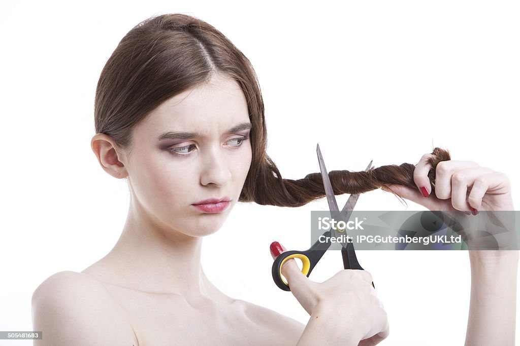 Portrait of attractive young woman Sad young woman with scissors cutting her hair over white background 20-24 Years Stock Photo