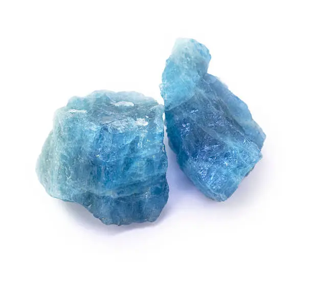 Photo of Blue aquamarine raw gemstones on the white background.