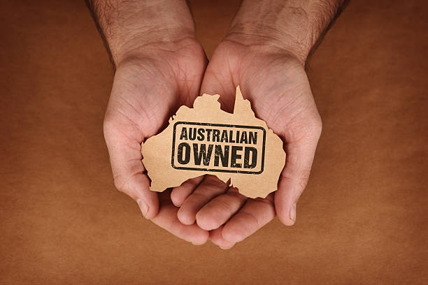 Australian Owned Stamped on Brown Paper Australia Shape in Hands stock photo