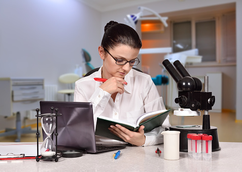 young female scientist reading a book sitting in laboratory