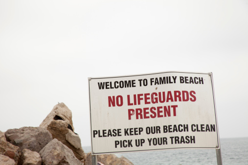 This sign warns that there are no lifeguards to assist swimmers in need of help and advising that trash andl itter shoud not be left on the beach