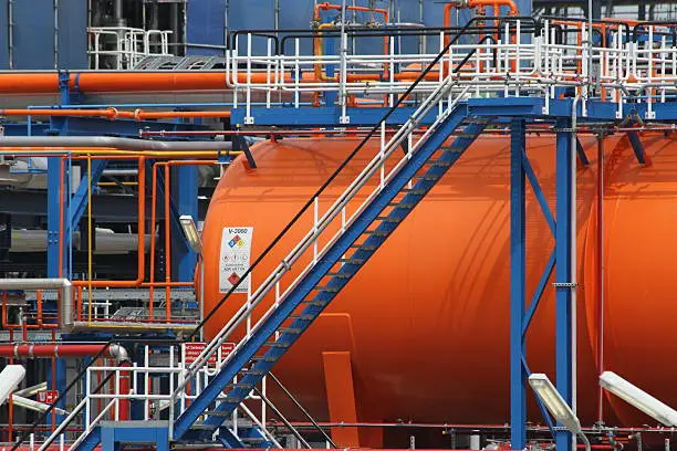 Orange chemical storage tank with blue ladder