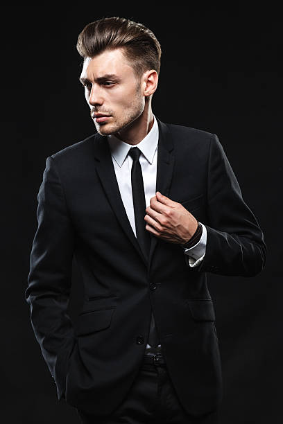 istock Handsome young man in suit on dark background 505502463