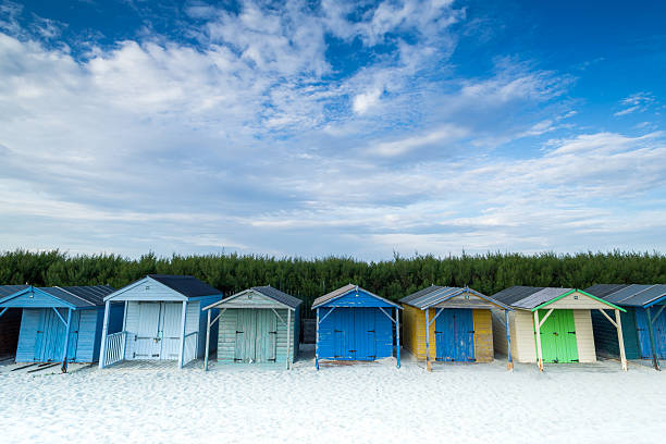 Beach Huts A row of multi-coloured beach huts on a sandy beach. chichester stock pictures, royalty-free photos & images