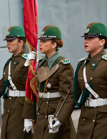 Santiago, Сhile - August 4, 2014: Female members of the Carabineros marching with a ceremonial flag as part of the changing of the guard ceremony at La Moneda in Santiago, Chile. La Moneda is the Presidential Palace in the centre of Santiago.