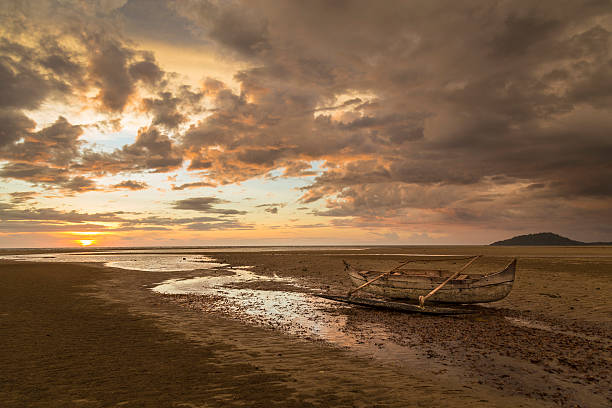 istock Old wooden sailor boat stranded on a sunset beach 505514318
