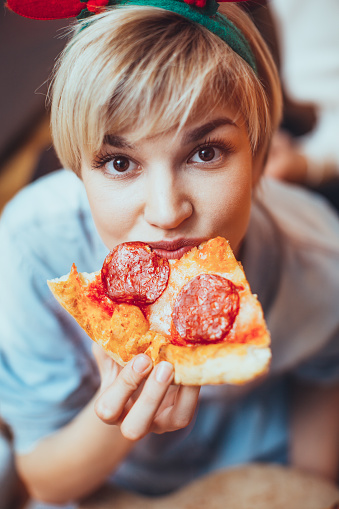 Portrait of young woman eating pizza