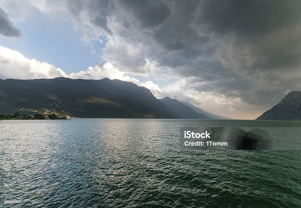 Dramatic view of famous Garda Lake (Lago di Garda), Italy. Dramatic clouds over famous Lake Garda (Lago di Garda), Italy. Activity Stock Photo