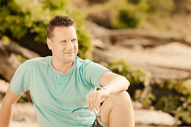 istock Fashion portrait handsome man sitting on tree 505518489