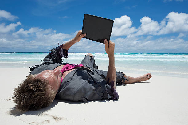 castaway homme d'affaires en utilisant une tablette sur plage tropicale - computer humor stranded business photos et images de collection