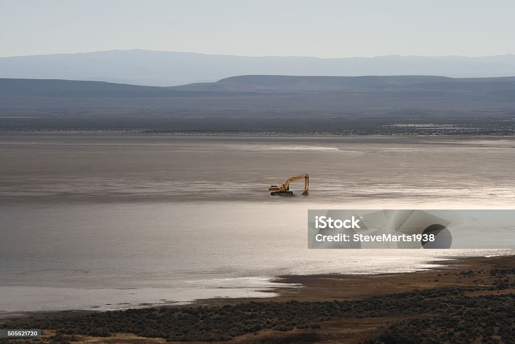 Walmart....coming soom  Far off excavator waiting for the signal to start digging on 100 million year old landscape.    Ancient lake bed with barren mountains beyond.  Desert Area Stock Photo