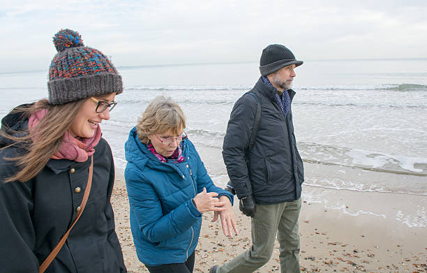 istock Father, mother and daughter walking on beach 505523636