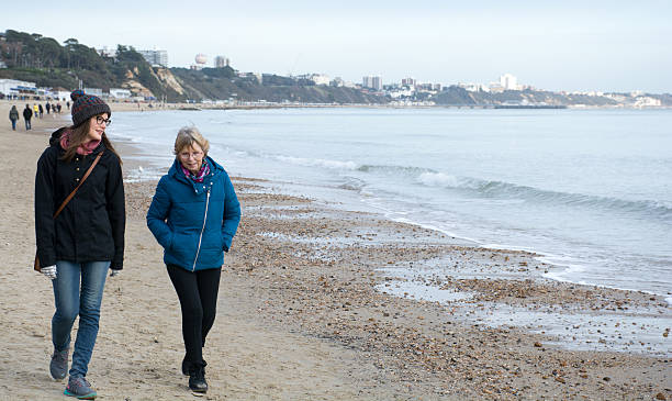 istock Two women chat as they walk by the sea 505523720