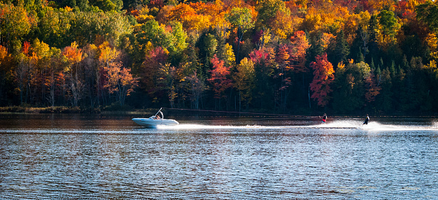 A pair of water skiers have fun on one of the last warm days of summer.  Water skiing in September on a northern Ontario lake.