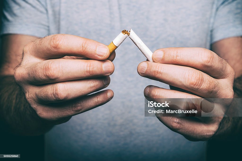 Quitting smoking - male hand crushing cigarette Quitting Smoking Stock Photo