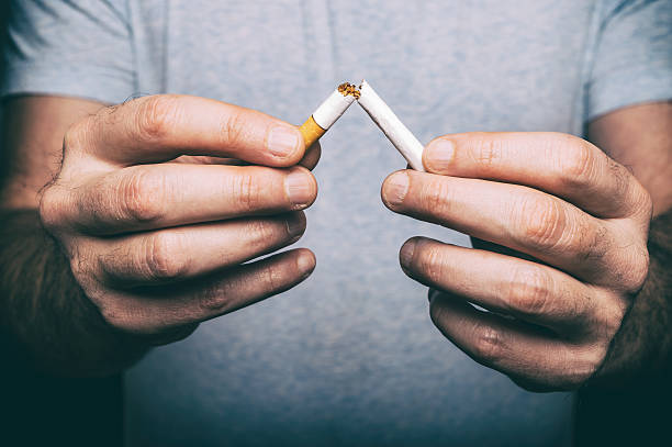Quitting smoking - male hand crushing cigarette stock photo