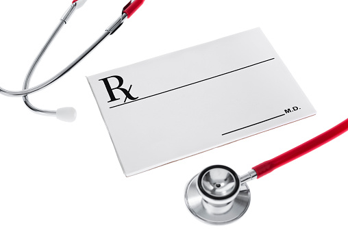 Looking down on a blank prescription pad with a red stethoscope wrapped around it, on white background