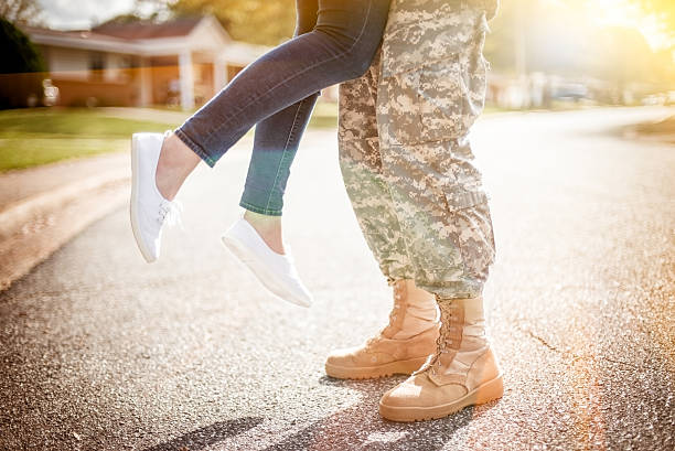 Young military couple kissing each other, homecoming concept, wa Young military couple kissing each other, homecoming concept, warm orange toning applied military deployment photos stock pictures, royalty-free photos & images